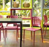 Ambiente com uma mesa preta e cadeiras vermelhas. 